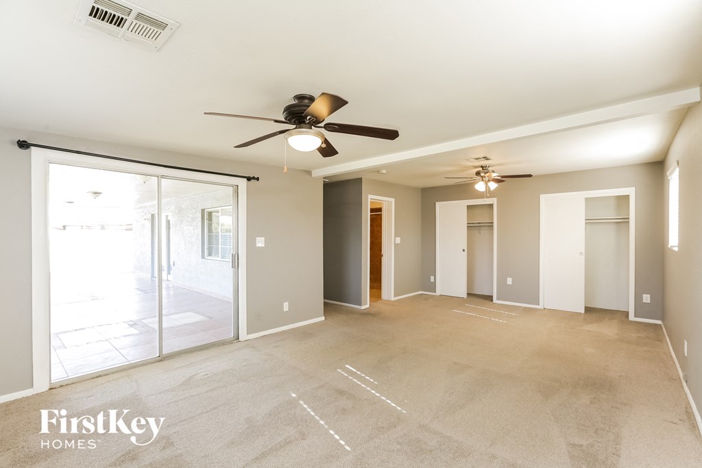 an empty living room with a ceiling fan and sliding glass doors