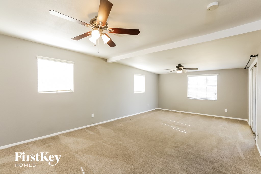 the spacious living room with ceiling fan and carpeting