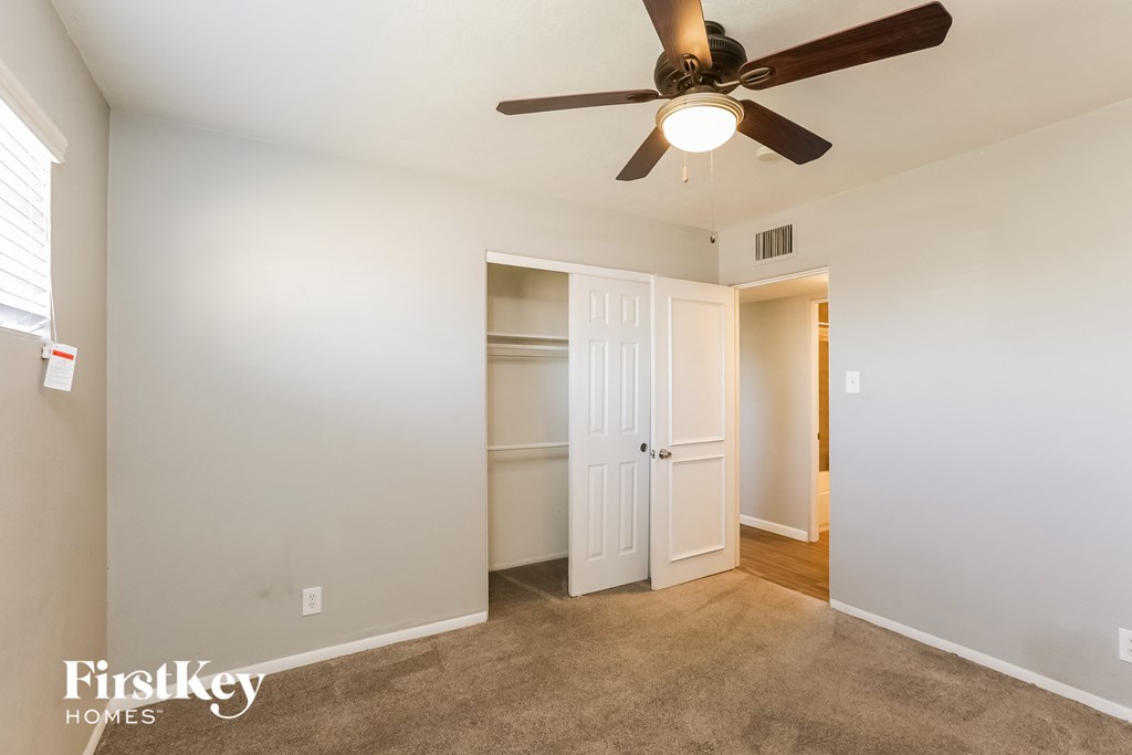 a bedroom with a ceiling fan and a closet