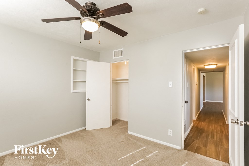a bedroom with a ceiling fan and a hallway to a closet