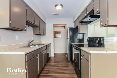 A kitchen with brown cabinets and a black fridge.