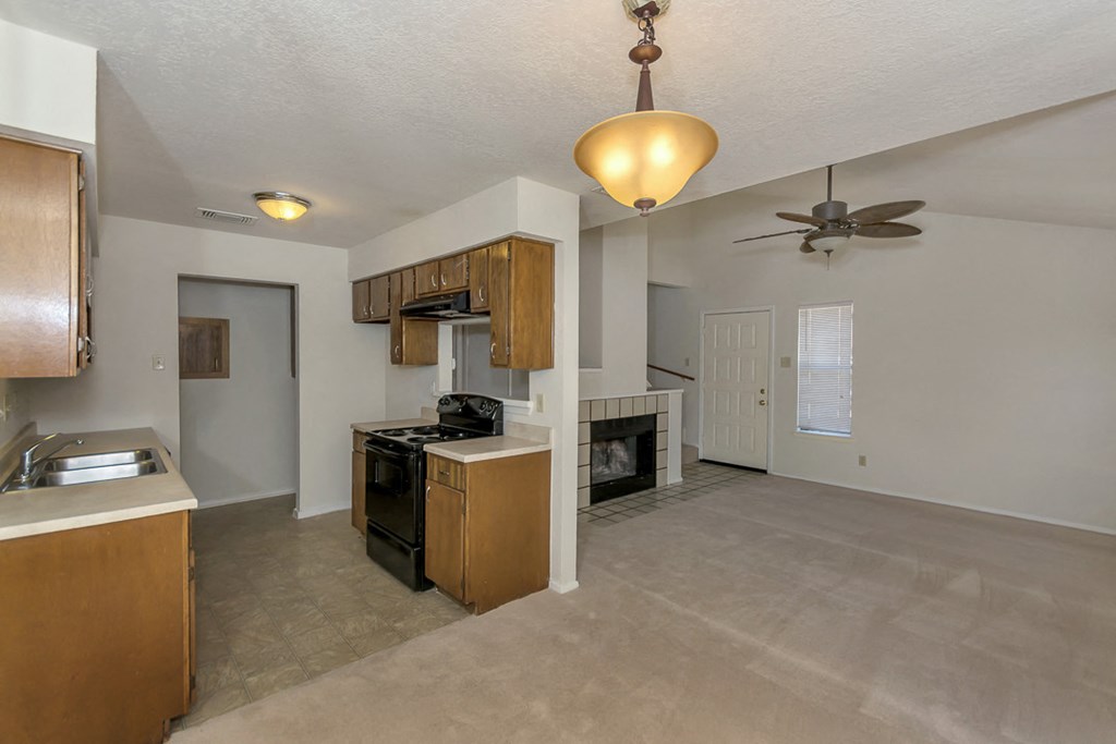 an empty kitchen and living room with a ceiling fan