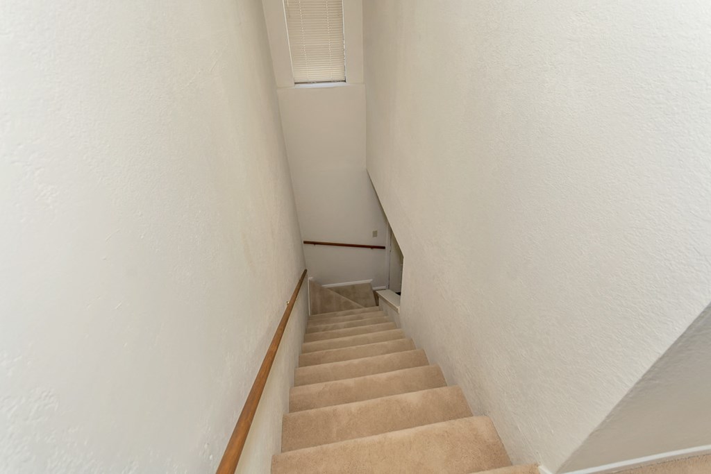 a flight of stairs with a white wall and a railing