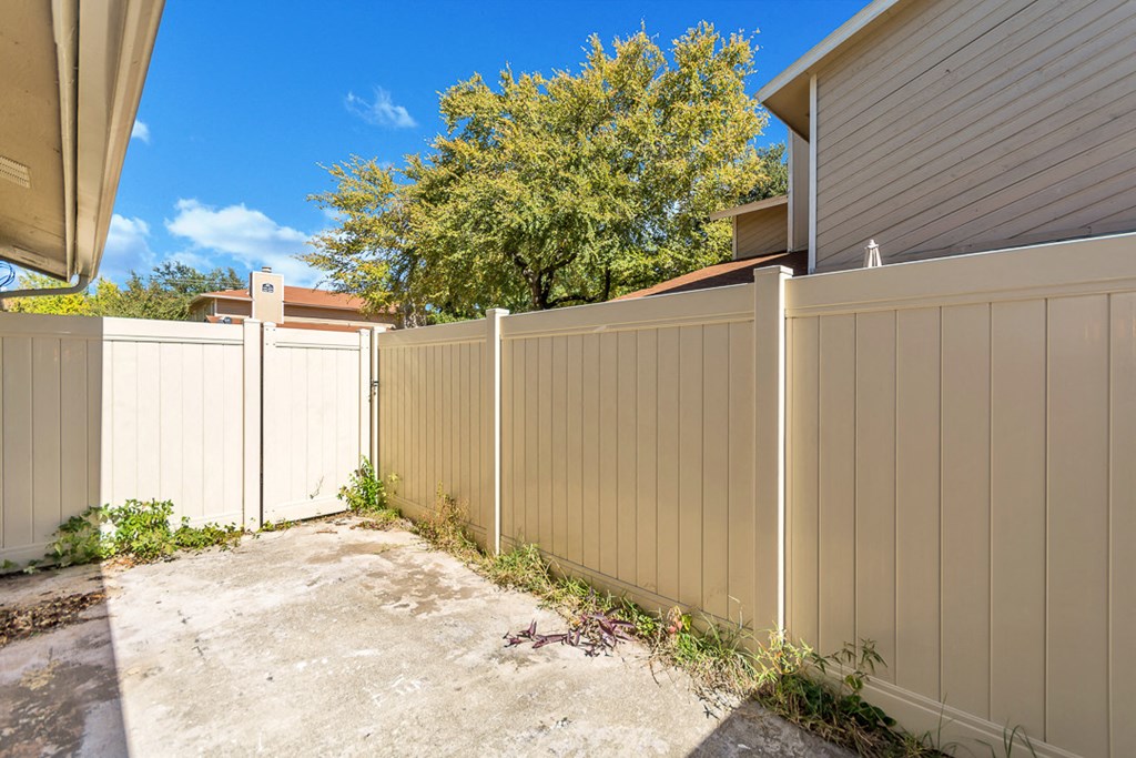 a white fence with a driveway in front of a house
