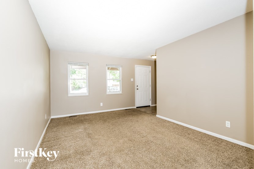 A room with a carpeted floor and a door is shown.