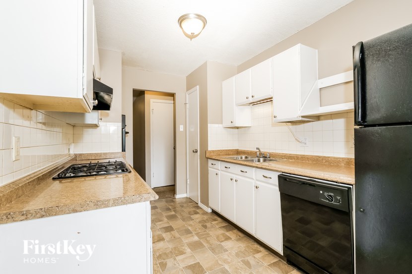A kitchen with a black refrigerator and white cabinets.