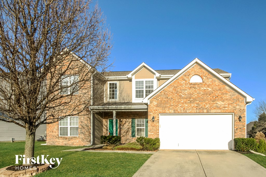 A brick house with a white garage door in front.