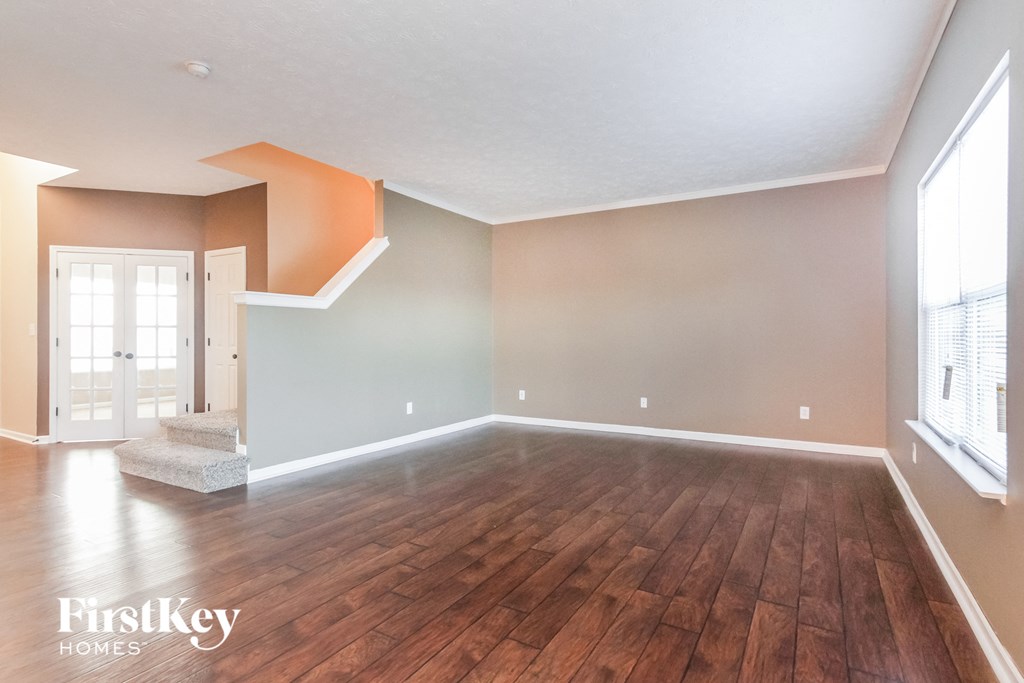 A room with wooden flooring and a window on the right side.