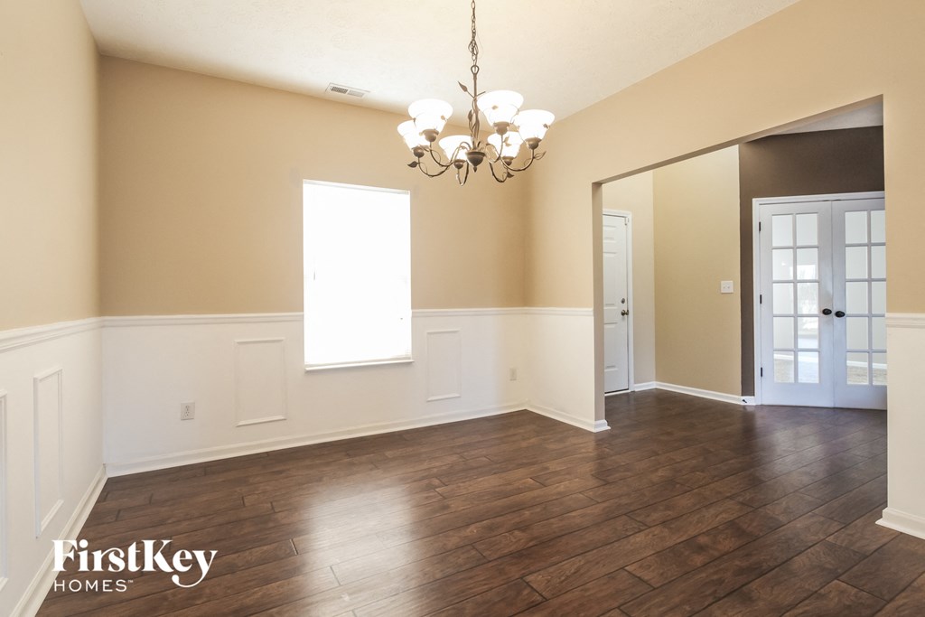 A large empty room with wooden floors and a chandelier.