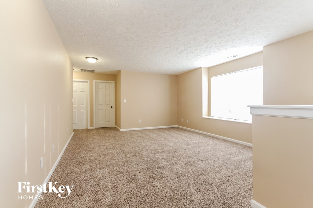 A room with a carpeted floor and a window letting in natural light.