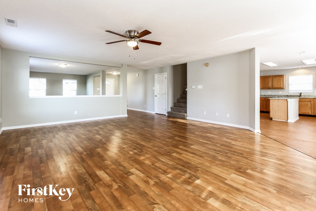 an empty living room with wood floors and a ceiling fan