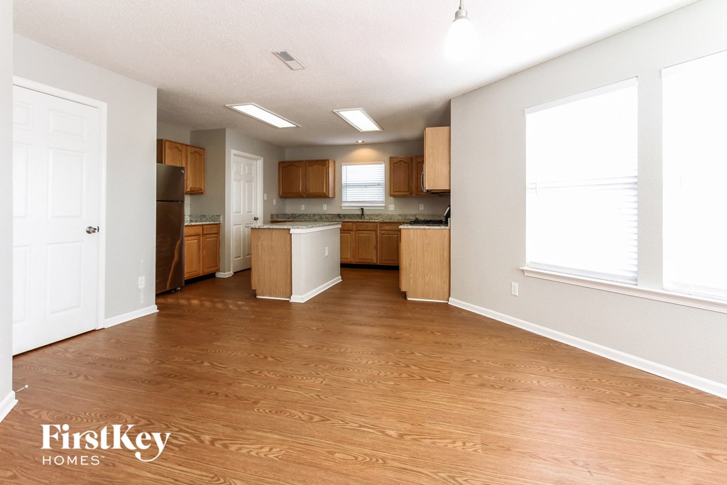 an empty kitchen with wood flooring and a large window