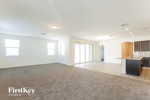 A spacious, empty room with a kitchenette and a dining area.