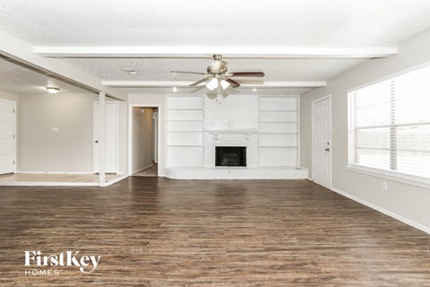 A spacious room with a fireplace and a ceiling fan.