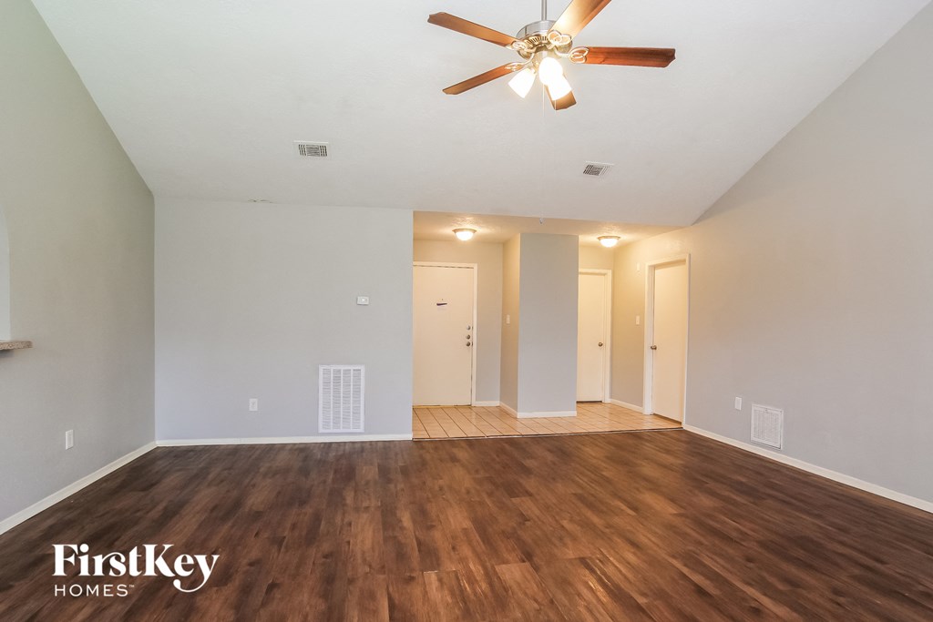 the living room of an empty house with a ceiling fan