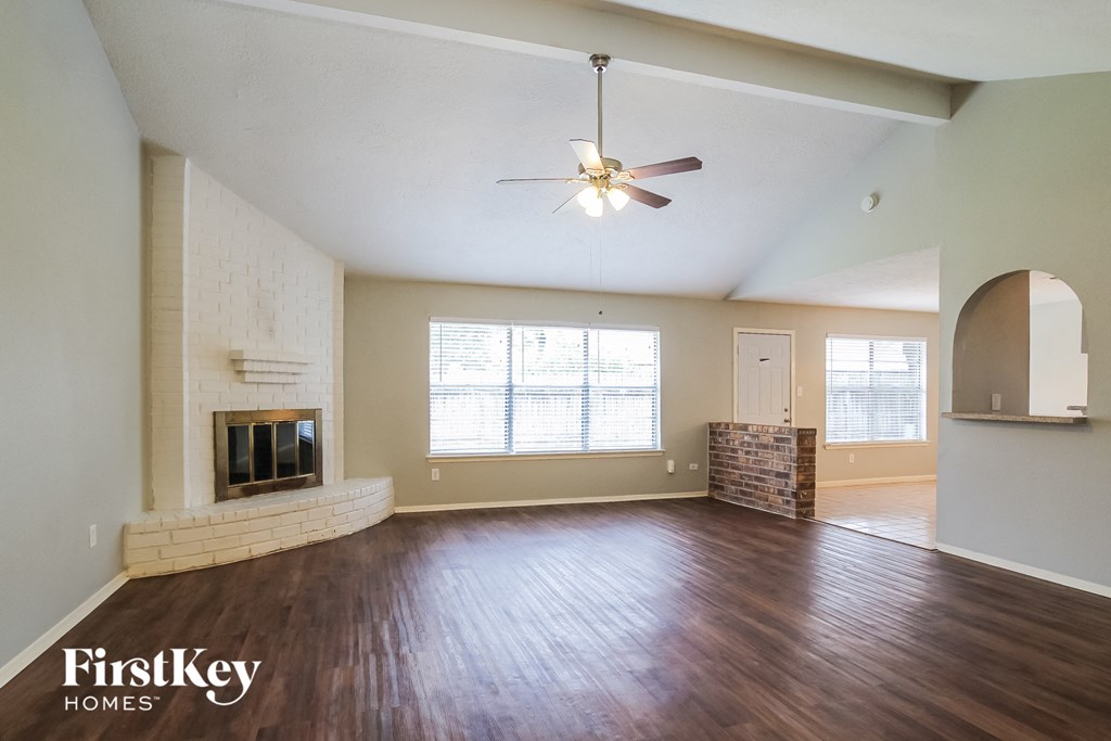 an empty living room with a fireplace and a ceiling fan