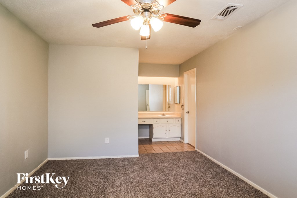 an empty living room with a ceiling fan and a bathroom