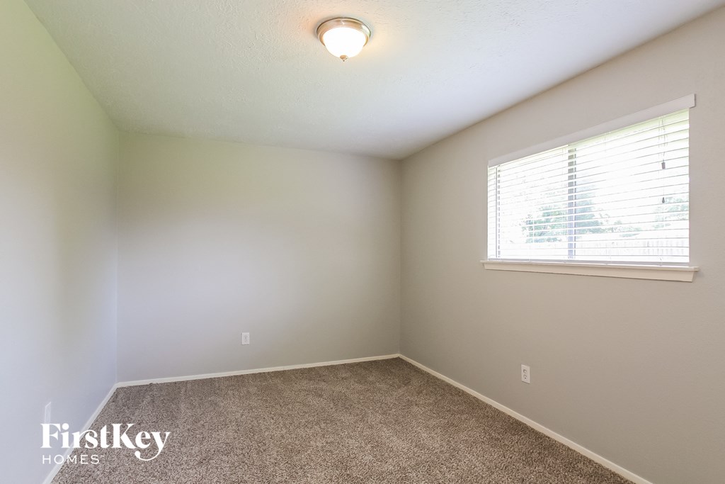 a bedroom with a large window and a carpeted floor