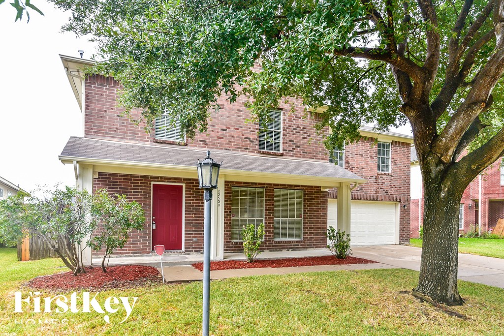 a brick house with a red door and a tree