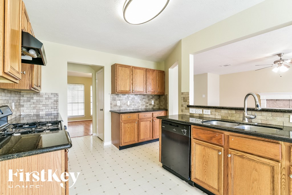 a kitchen with wooden cabinets and a black dishwasher and a sink