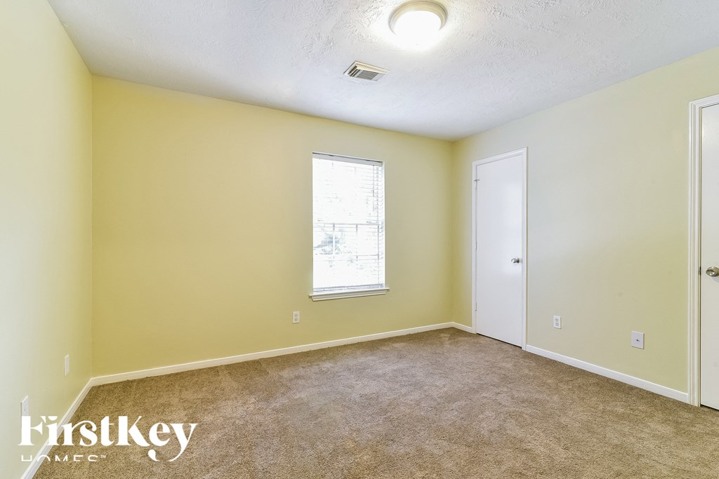 a bedroom with yellow walls and carpet and a white door and window