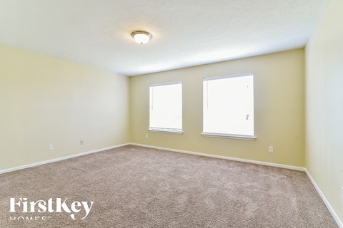 the spacious living room with two windows and beige carpet