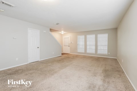 a spacious living room with carpet and a white door