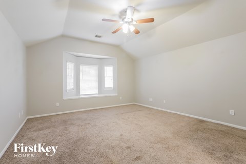a bedroom with carpet and a ceiling fan and a window