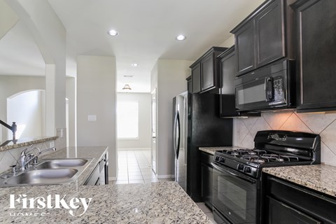 A kitchen with black cabinets and a granite countertop.