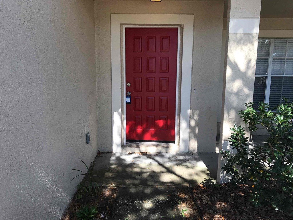 A red door is on the left side of a white wall.