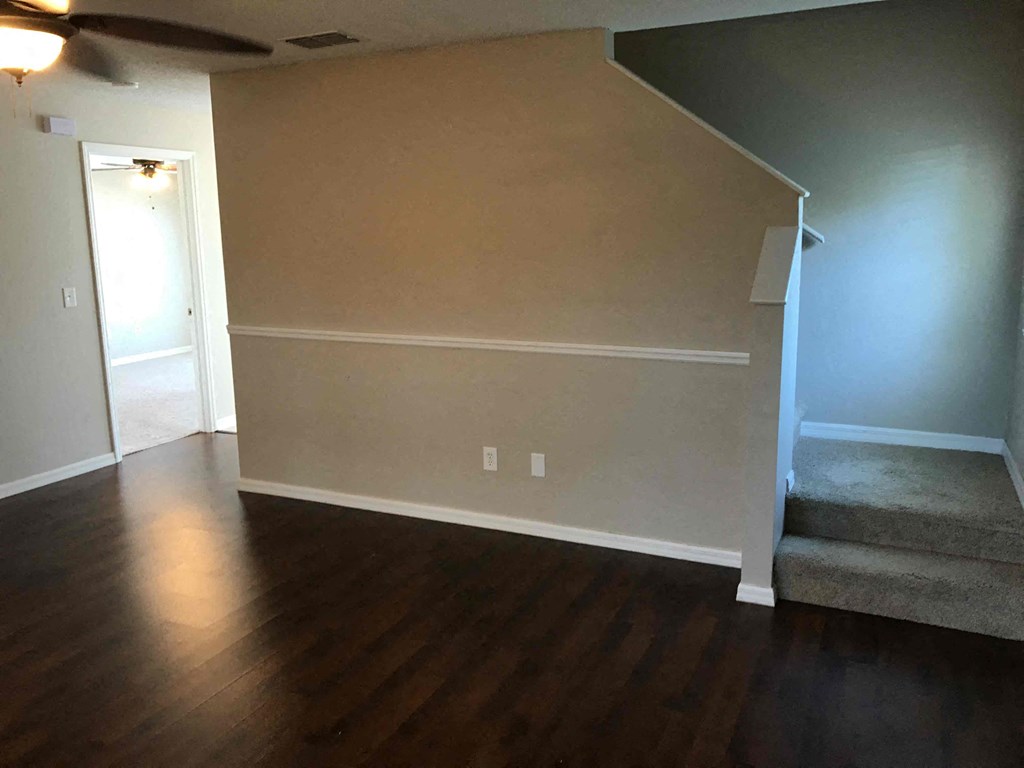 A room with a wooden floor and a staircase.