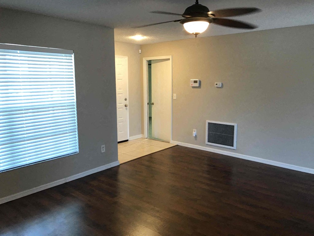 A room with a ceiling fan and a door leading to another room.