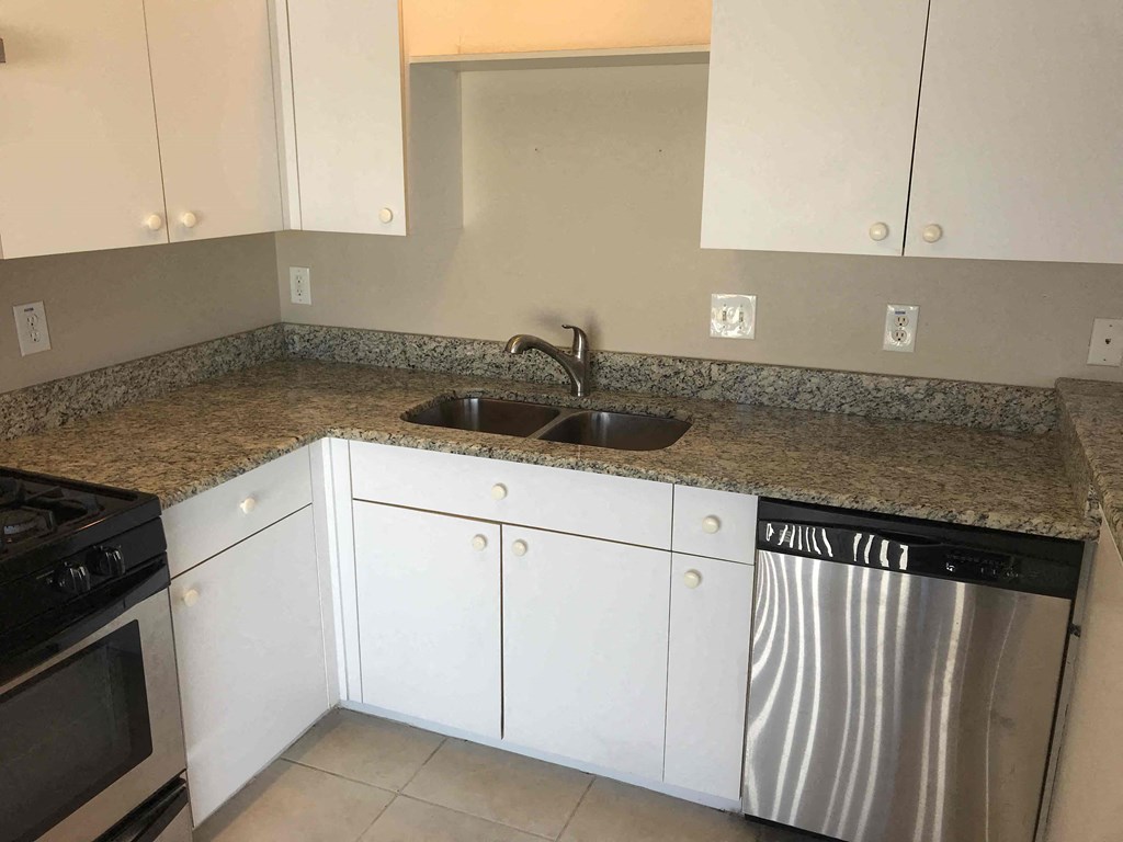 A kitchen with a granite countertop and white cabinets.