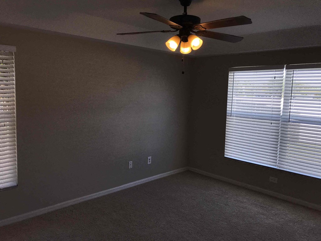 A room with a ceiling fan and a window with blinds.