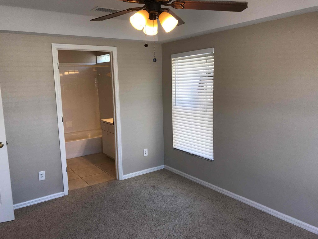 A room with a ceiling fan and a window with blinds.