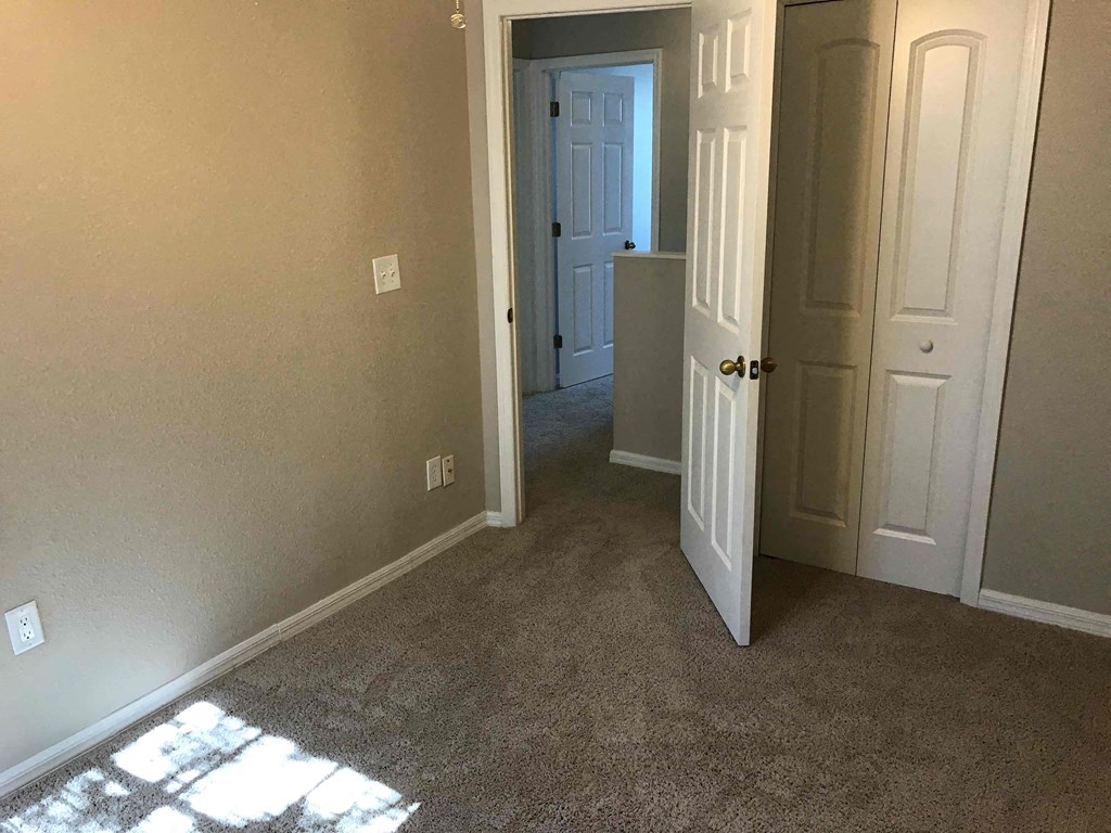 A room with a carpeted floor and a doorway leading to another room.