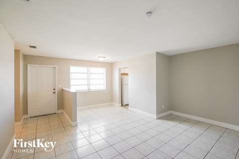 A spacious room with a door, a window, and a tiled floor.
