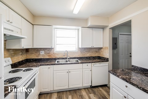 A kitchen with white cabinets and a black countertop.