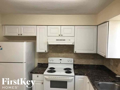 A kitchen with white appliances and cabinets.
