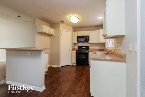 A kitchen with a black stove top oven and a sink with a granite counter top.
