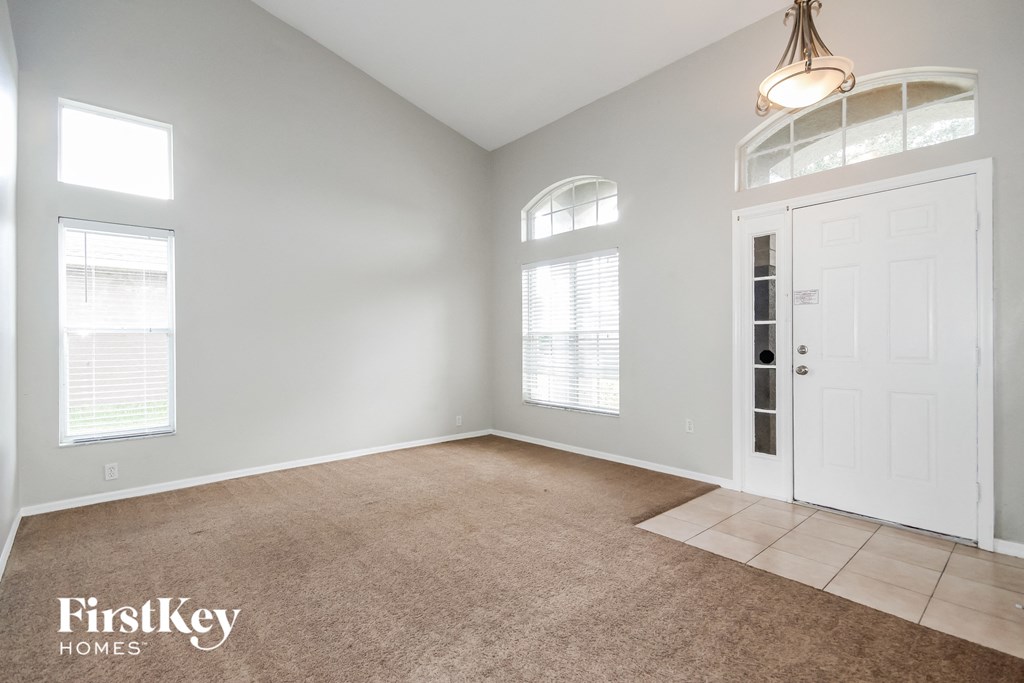 A room with a carpeted floor, a door, and two windows.