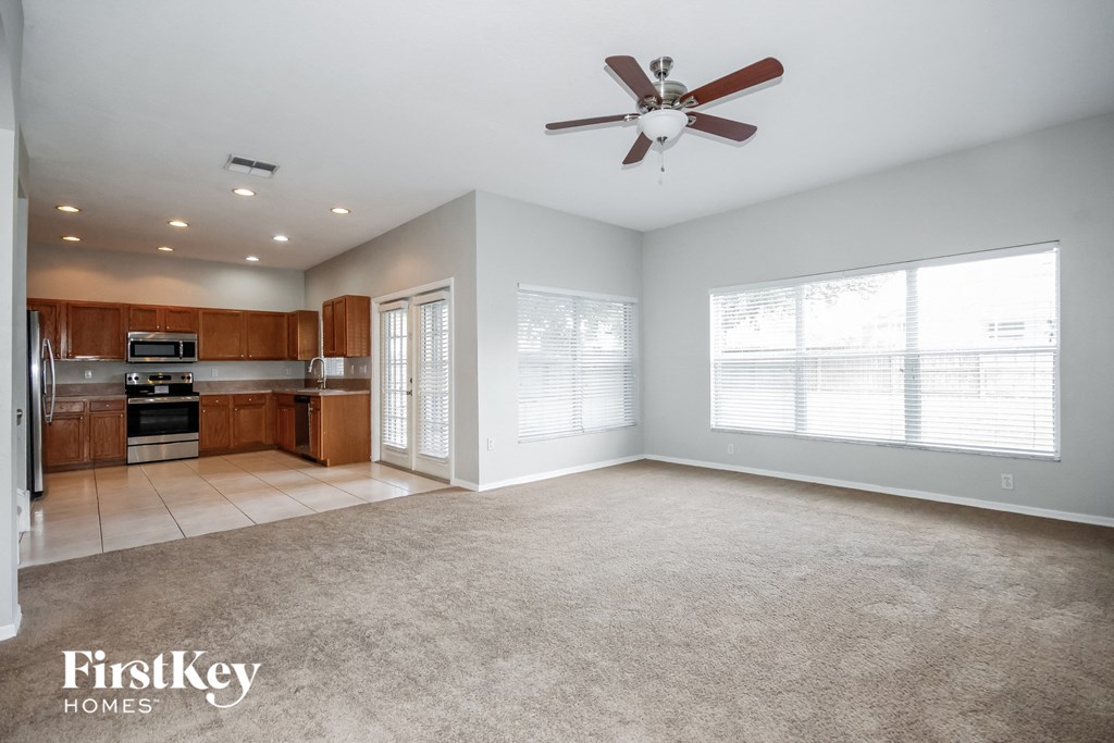 A spacious living room with a carpeted floor and a ceiling fan.
