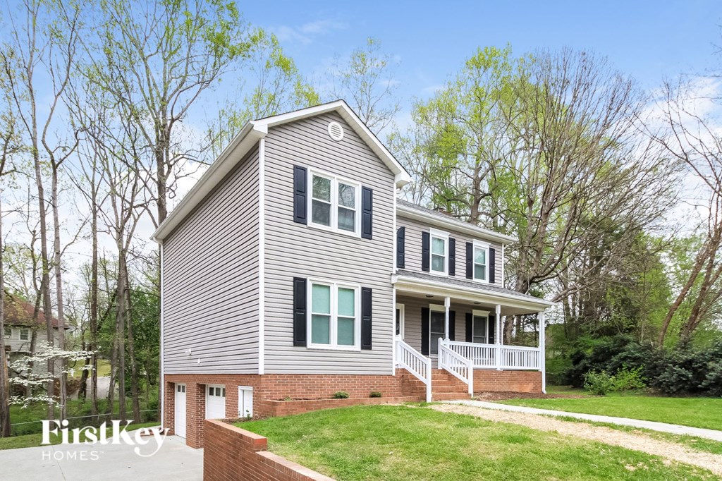 a gray house with green shutters and a lawn