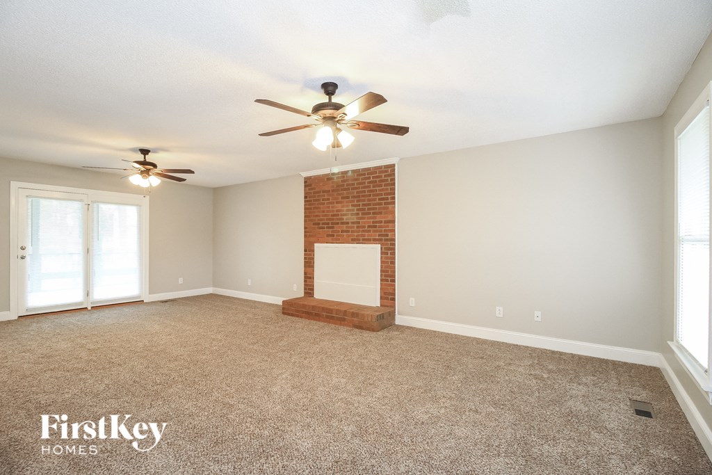 an empty living room with a ceiling fan and a fireplace