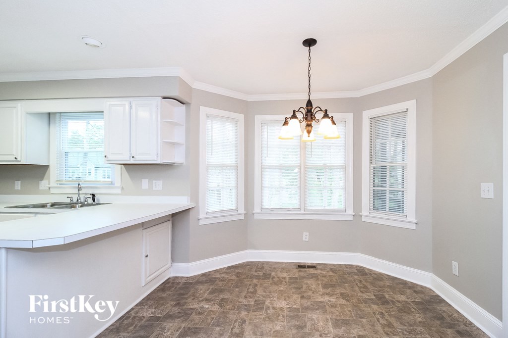 an empty dining room with a kitchen and a chandelier