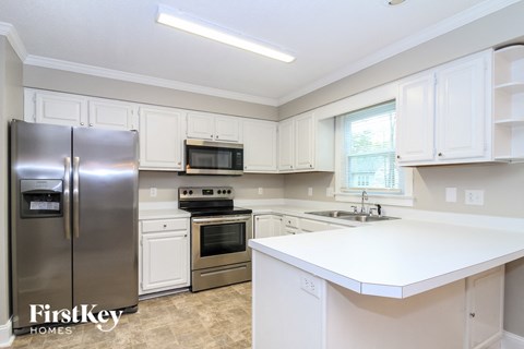 a white kitchen with stainless steel appliances and white counter tops