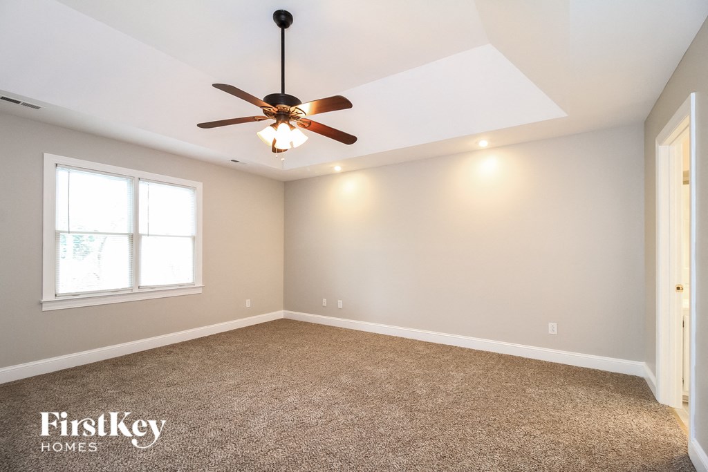 the master bedroom has a carpeted floor and a ceiling fan