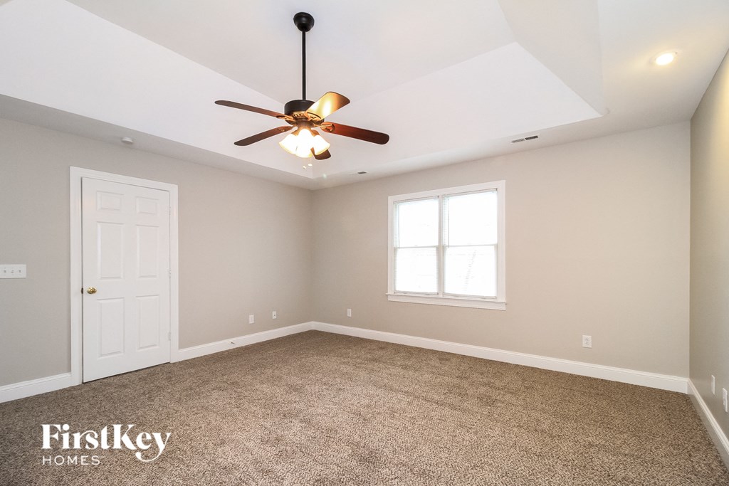 the master bedroom has a ceiling fan and a carpeted floor