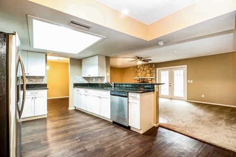 A kitchen with a refrigerator on the left and a counter with a sink.