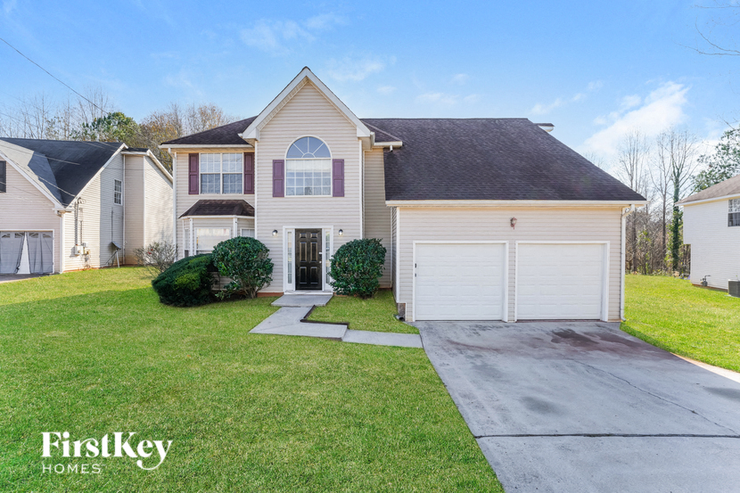 a beige house with a white garage door and a green lawn